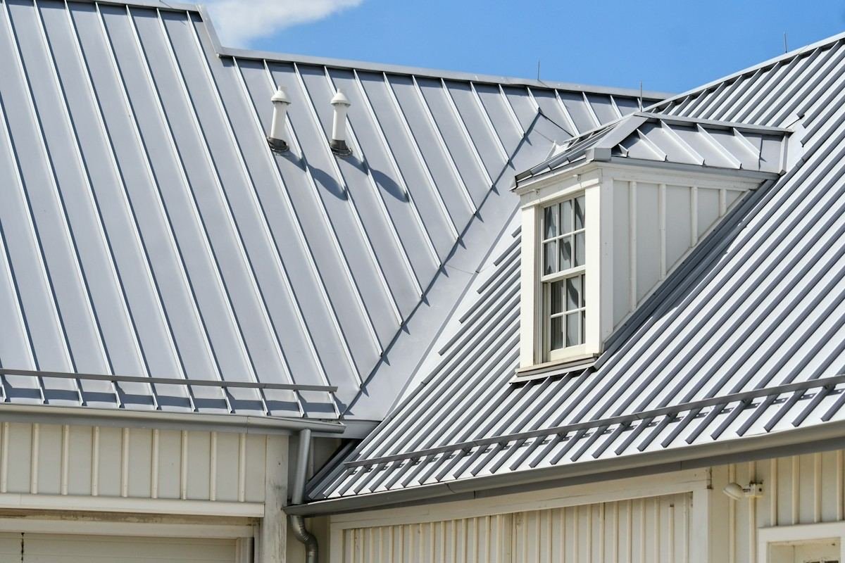 A silver standing-seam metal roof with a white dormer window