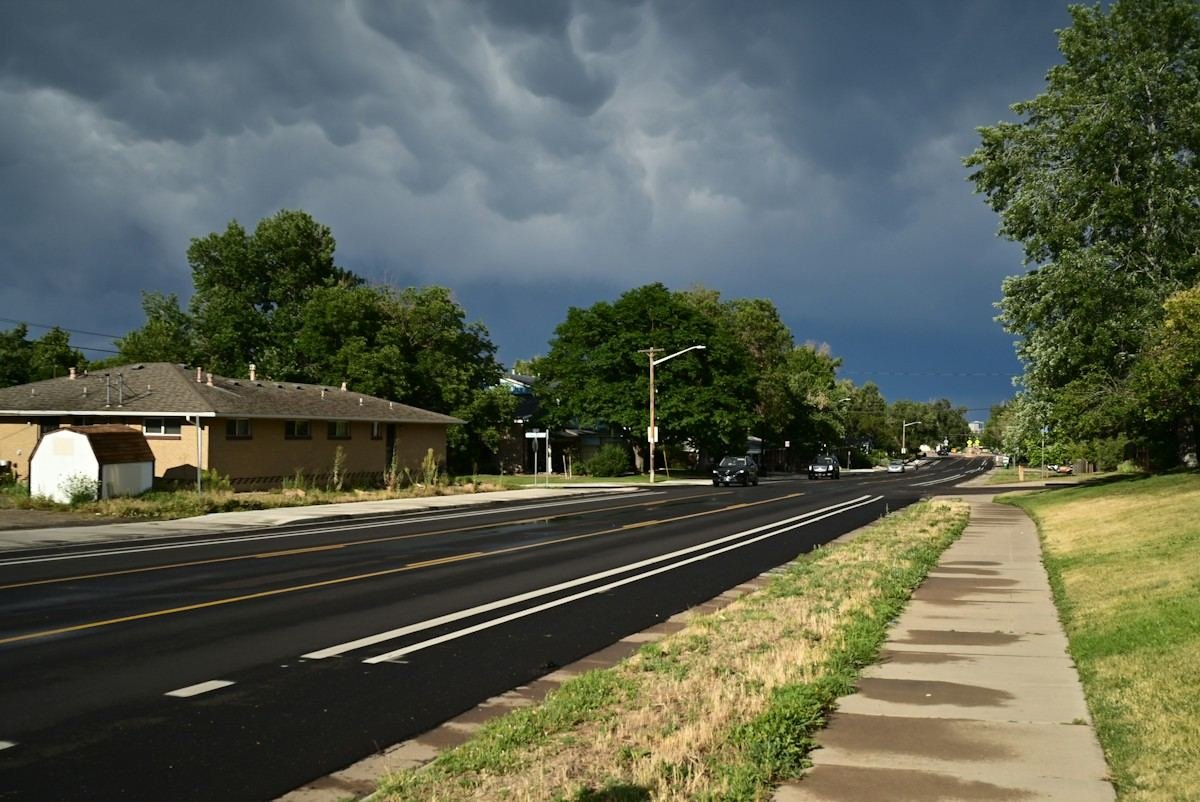 Dark storm clouds building over a ranch house and a wide road